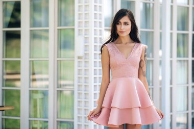 Sokak kafede poz pembe elbise güzel gülümseme ile çekici genç kadın