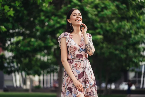 Lachendes Mädchen im Kleid mit Tätowierung auf den Händen posiert von Grün auf dem Hintergrund — Stockfoto