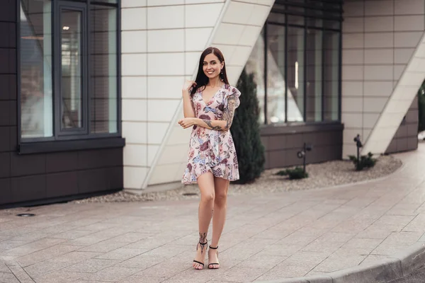 Привлекательная брюнетка в цветном платье позирует возле бизнес-центра . — стоковое фото