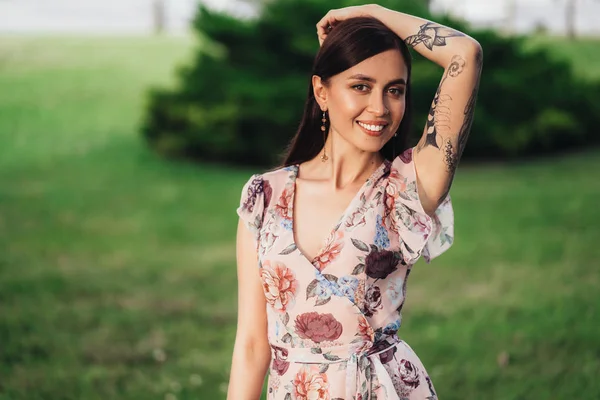 Smiling girl in dress with tattoo on her hands posing of greenery on background — Stock Photo, Image