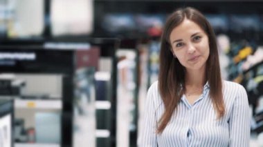 Kozmetik mağazasında ki kızın kameraya bakıp gülme, yavaş çekim portresi