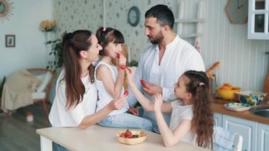 Mutfakta mutlu aile, anne, baba ve kızları çilek yemek, yavaş hareket