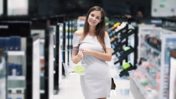 Портрет девушки в косметическом магазине улыбающейся и смотрящей в камеру, замедленной съемки — стоковое видео