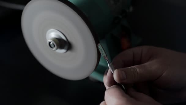 Close-up, werknemer verscherpt manicure tools op Grindstone, schittert in slow-motion — Stockvideo