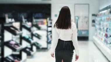 Backside görünümü, kadın raflar boyunca kozmetik mağazasına gider, yavaş hareket