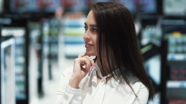 El retrato de la muchacha hermosa en la tienda cosmética mira la cámara y sonríe — Vídeo de stock