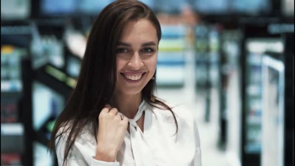 Retrato de menina na loja de cosméticos olha para a câmera e sorri, câmera lenta — Vídeo de Stock