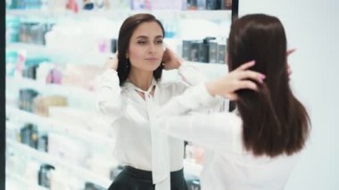 Güzel genç kadın kozmetik mağazasında ayna önünde kendini preens