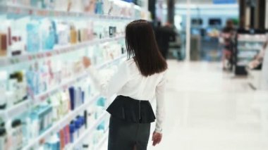 Kozmetik dükkanında Pretty kız yüz kremi seçer, malzemeler okur, yavaş hareket