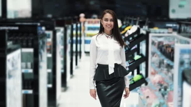 El retrato de la muchacha hermosa en la tienda cosmética mira la cámara y sonríe — Vídeo de stock