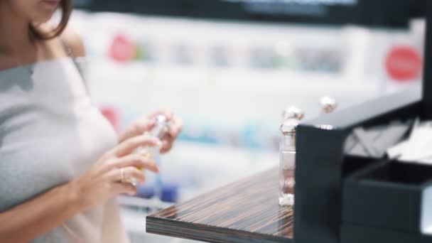 Gros plan de parfum en vitrine, fille acheteur prend et renifle, au ralenti — Video