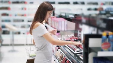 Genç güzel kadın kozmetik mağazasında ruj seçer, yavaş hareket
