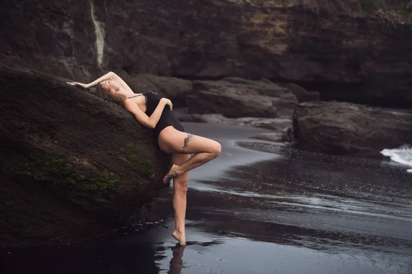 Junge sexy Frau im Badeanzug ruht im Urlaub am schwarzen Sandstrand — Stockfoto