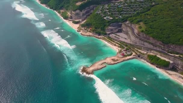 Вид з повітря на частину острова з бірюзовими океанськими хвилями, вілли на скелі в зеленому — стокове відео