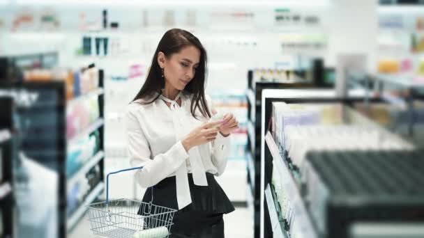 Pretty girl in cosmetics shop chooses body spray, puts it in basket — Stock Video