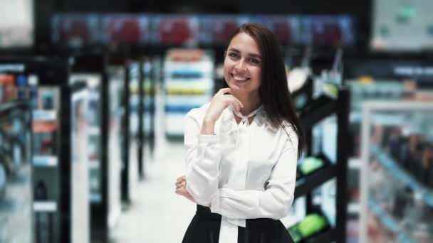 Portret van mooi meisje in cosmetische winkel kijkt naar camera en glimlacht — Stockvideo