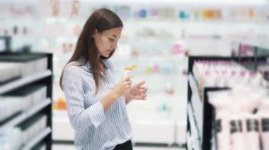 Kozmetik mağazasında güzel kız krem seçer, kız açar ve onu kokur
