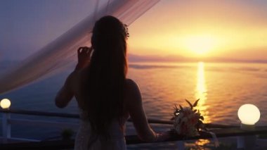 Gelin silueti kafe terasında güzel gün batımı bakar, yavaş hareket