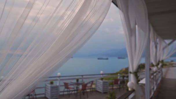 Fluttering white curtains at open air on terrace by sea, slow motion — Stock Video