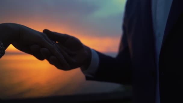 Närbild siluett av händerna på nygifta på solnedgång bakgrund, slow motion — Stockvideo
