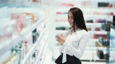 Kadın kozmetik mağazasında parfüm seçer, test üzerine spreyler ve koklar