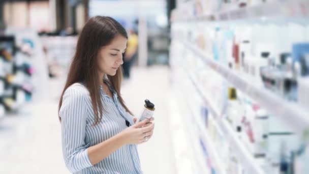 Jovem mulher na loja de cosméticos escolhe cara tônica, cheira, câmera lenta — Vídeo de Stock