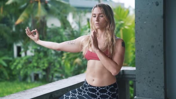 Jonge vrouw doet yoga oefening, stretching buiten met groen op achtergrond — Stockvideo