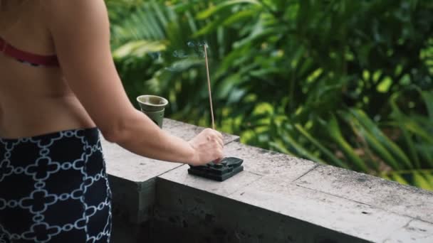 Close-up van dames handen zetten aromatische stok op stand, groen op achtergrond — Stockvideo