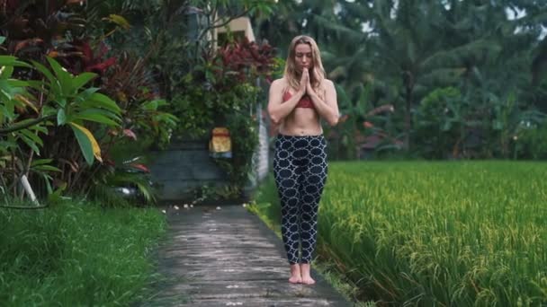 Mujer joven haciendo ejercicios de yoga y estiramiento al aire libre, vegetación en el fondo — Vídeos de Stock