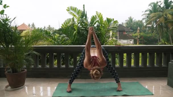 Mujer fitness disfrutando practicando yoga en balcón con palmeras en el fondo — Vídeos de Stock