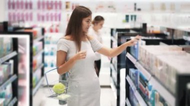 Kozmetik dükkanında Pretty kız vücut kremi seçer, koklar, yavaş hareket