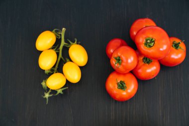 Siyah ahşap arka plan üzerinde kase içinde sarı ve kırmızı kiraz domates üst görünümü