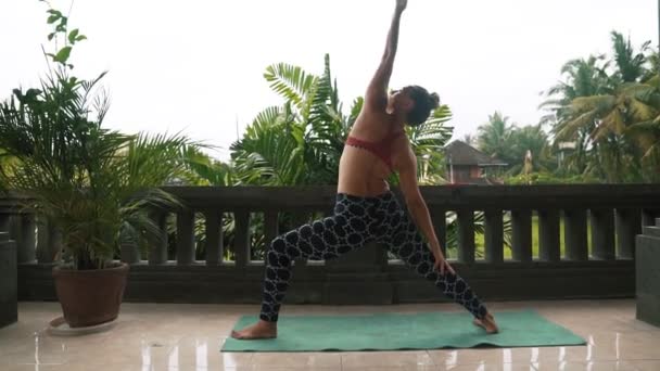 Mujer fitness disfrutando practicando yoga en balcón con palmeras en el fondo — Vídeos de Stock