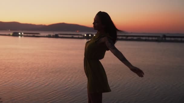 Sziluettje fiatal nő naplementekor, terjed a karját tágra nyílt, lassú mozgás — Stock videók