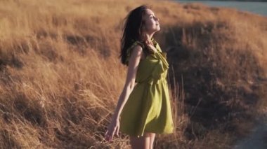 Güzel kadın gün batımında sahada duruyor ve derin, yavaş hareket nefes alır