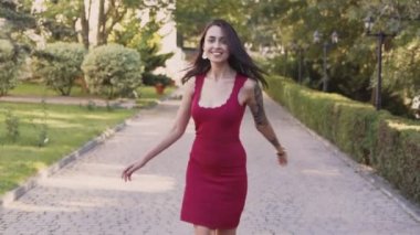 Kadının arka dan görünümü parkta yürür, döner ve kameraya gülümsüyor, yavaş çekim