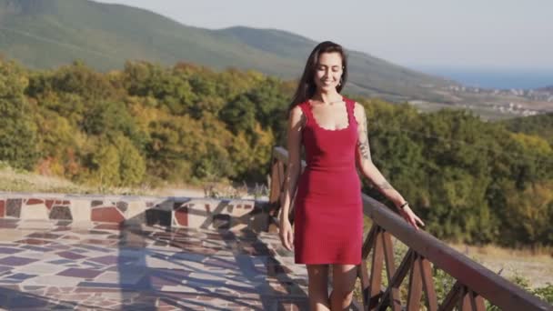 Mujer va a la cámara, sonrisas, hermosa vista de la naturaleza en el fondo, cámara lenta — Vídeos de Stock