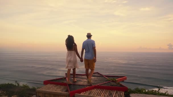 Вид ззаду, пара закоханих, які дивляться на красивий захід сонця, обіймаються, повільний рух — стокове відео