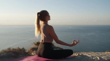 Kadın mat üzerinde lotus yoga pozisyonu oturur ve açık havada meditasyon, yavaş hareket