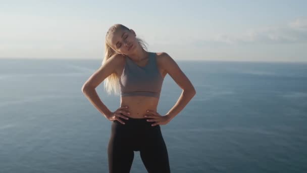 Dziewczyna robi ćwiczenia rano na klifie o świcie z widokiem na ocean, powolny ruch — Wideo stockowe