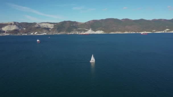 Imagens aéreas de iate à vela branco na água do mar em dia ensolarado, visão de ângulo largo — Vídeo de Stock