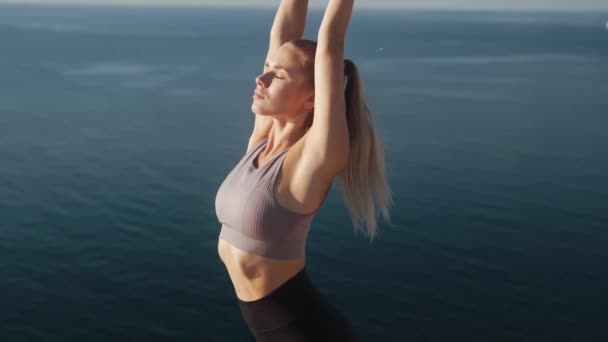 Жінка робить вправи і тягнеться вранці з видом на море, повільний рух — стокове відео