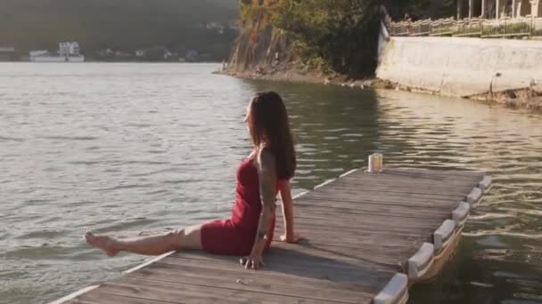 Γυναίκα κάθεται σε ξύλινη προβλήτα, πιτσιλίσματα με τα πόδια της στη λίμνη νερό, αργή κίνηση — Αρχείο Βίντεο