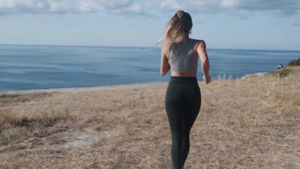 Vista trasera de la mujer corriendo al aire libre, hermosa vista sobre el océano, cámara lenta — Vídeos de Stock
