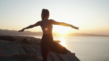 Gün doğumunda dağın tepesinde kadın uygulamaları yoga backside görünümü, yavaş hareket