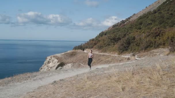 山の中を走る女性の裏側の眺め、海の美しい景色、スローモーション — ストック動画