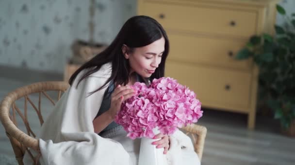 Feliz joven mujer se sienta en sillón sostiene ramo de flores, olfatea, sonríe — Vídeo de stock