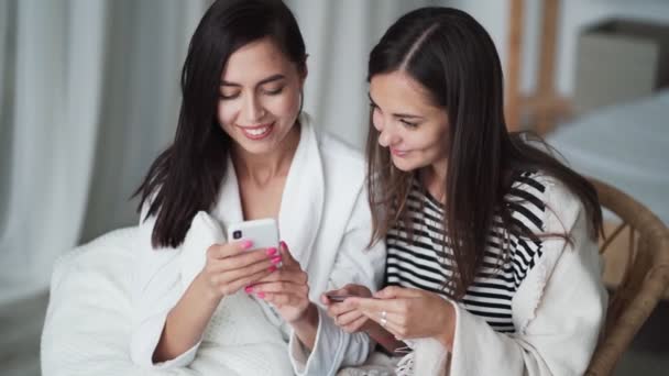 Gros plan, deux filles magasinent en ligne, entrer des données dans le téléphone à partir de la carte bancaire — Video