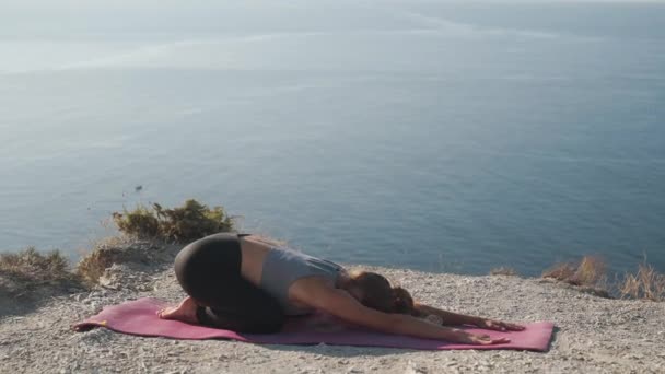 Mulher faz exercícios de ioga e se estende pela manhã com vista sobre o mar, câmera lenta — Vídeo de Stock