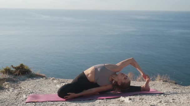 Femme fait des exercices de yoga et s'étend le matin avec vue sur la mer, au ralenti — Video